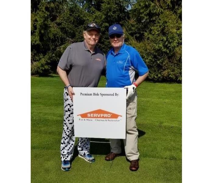 Ian McCutcheon and Dave take a picture with the SERVPRO Logo