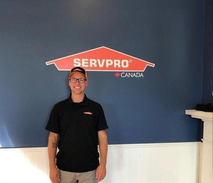 male employee smiling in front of SERVPRO logo